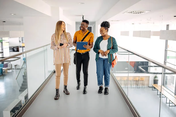Three young professionals walking together in open working space-type office building, smiling