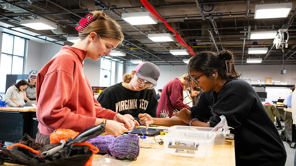 A group of engineering students wearing safety goggles collaborate on a project in a makerspace on campus
