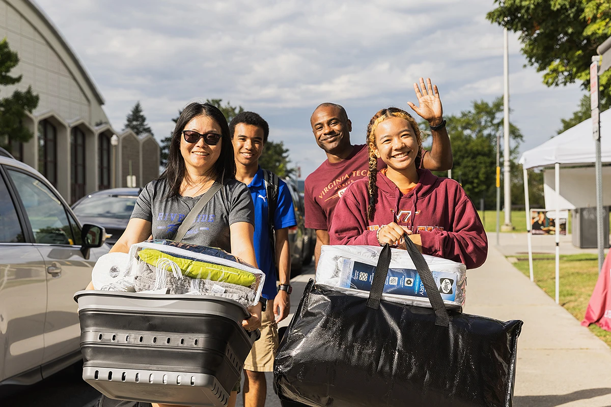 A group of four people, smiling while carrying bags and baskets, moving in.