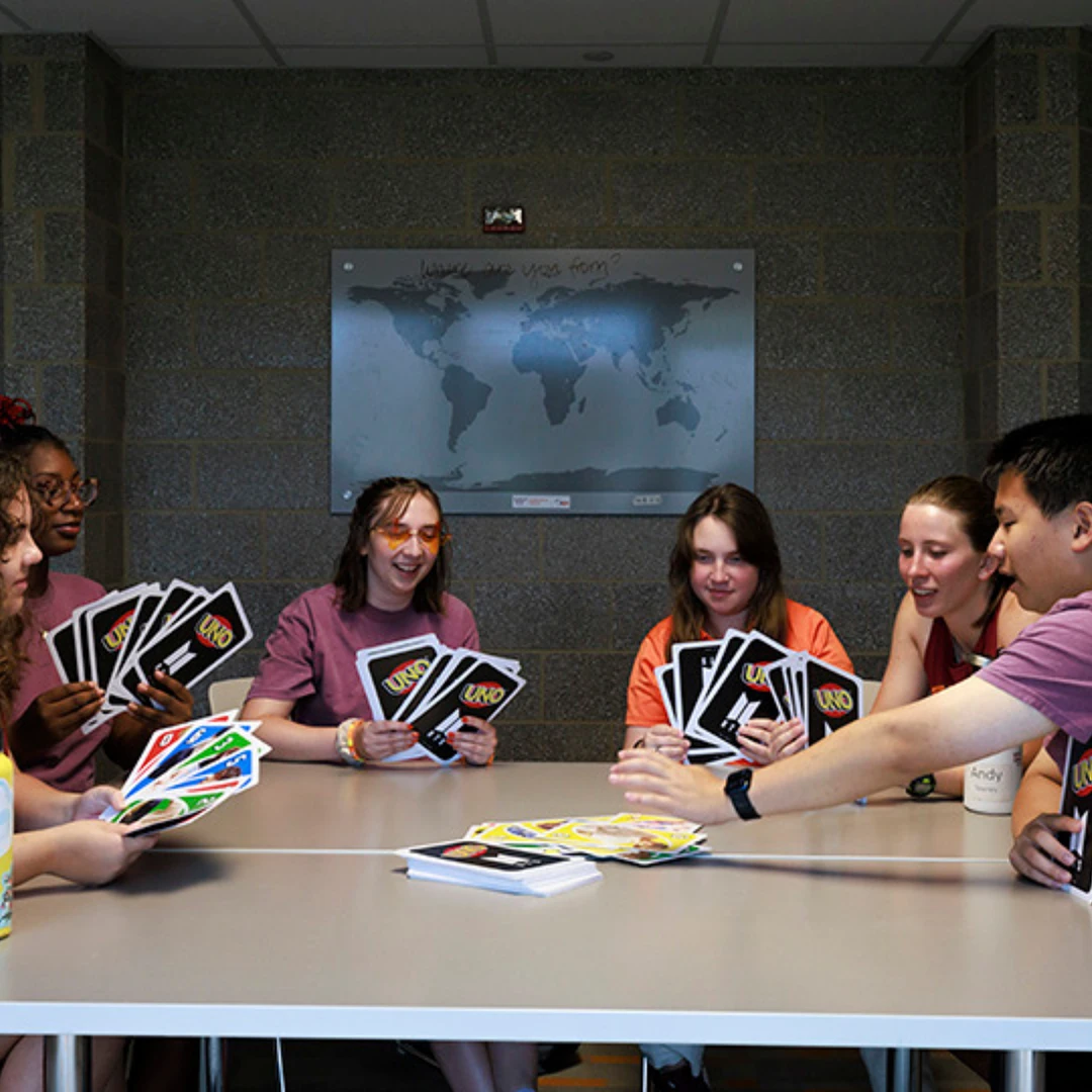 A group of people is gathered around a table playing a game of UNO with oversized cards.
