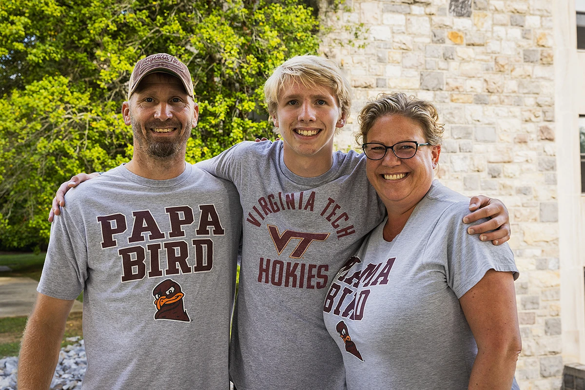 A smiling family poses together, wearing matching Virginia Tech-themed shirts.